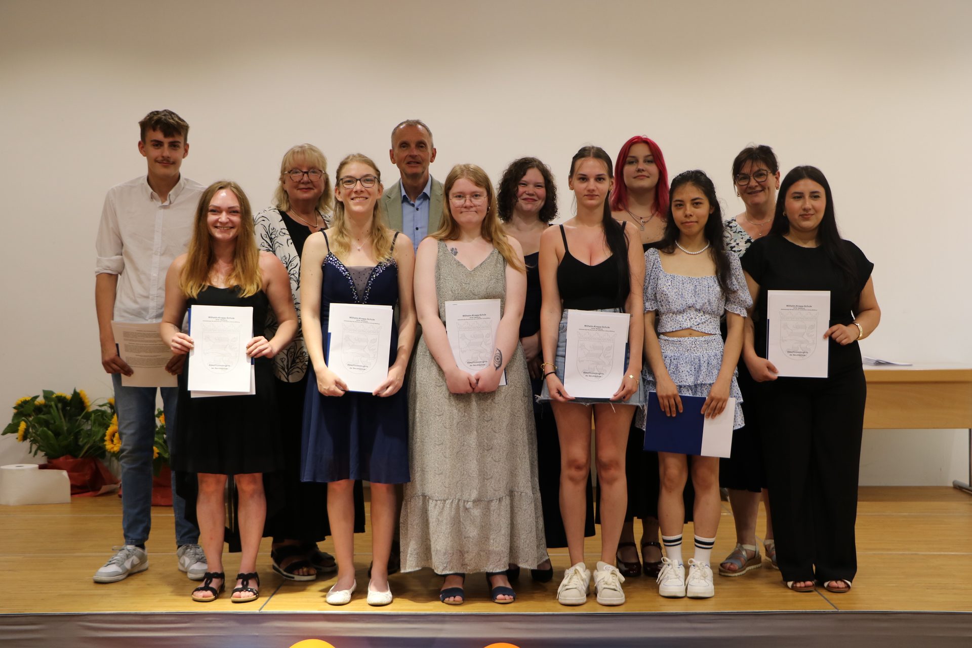 Die geehrten Absolventinnen und Absolventen der Einzelhandels- und Verkäuferklassen mit ihren Zeugnissen bei der Abschlussfeier in der Aula der Wilhelm-Knapp-Schule Weilburg 2026