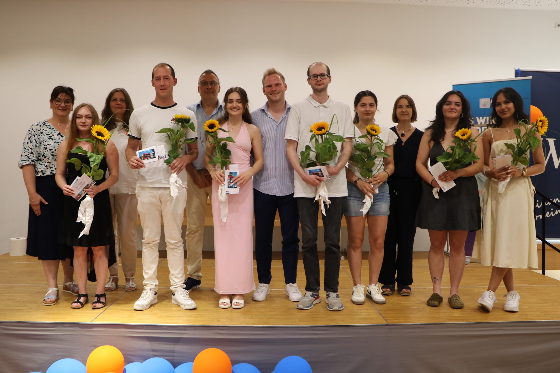 Die besten Absolventinnen und Absolventen der Einzelhandels- und Verkäuferklassen mit Sonnenblumen und Präsenten bei der Abschlussfeier an der Wilhelm-Knapp-Schule Weilburg 2026
