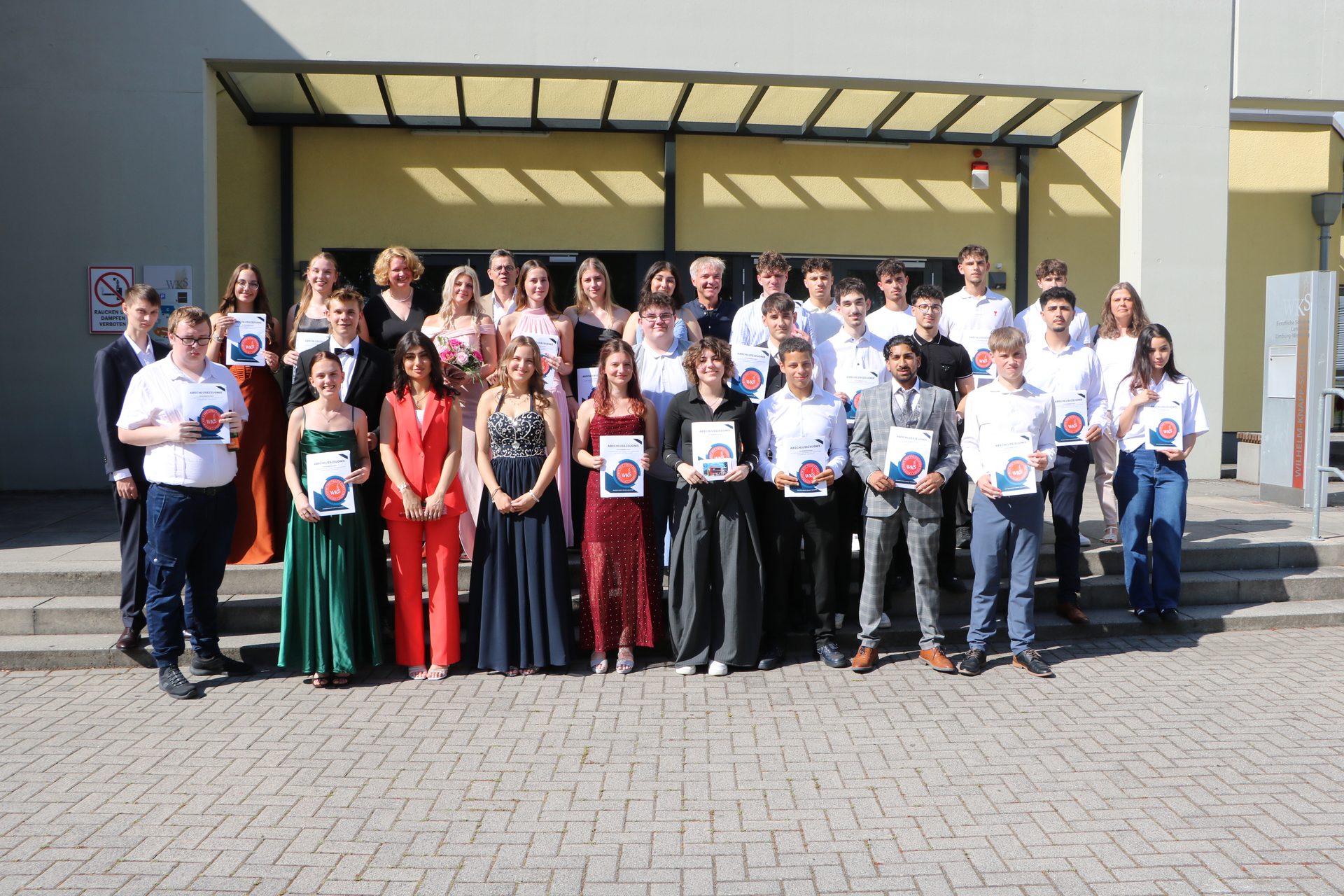 Absolventinnen und Absolventen der Fachoberschule (FOS) Wirtschaft und Verwaltung mit ihren Abschlusszeugnissen vor der Wilhelm-Knapp-Schule Weilburg 2026